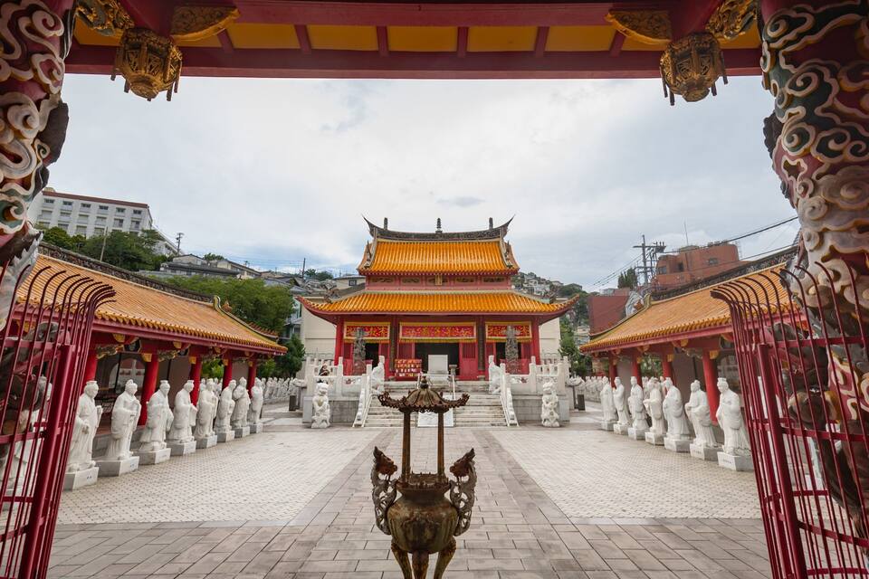 Ein traditioneller chinesischer Tempel mit aufwendiger Architektur, einer zentralen Statue und Reihen von Schutzgottheiten.