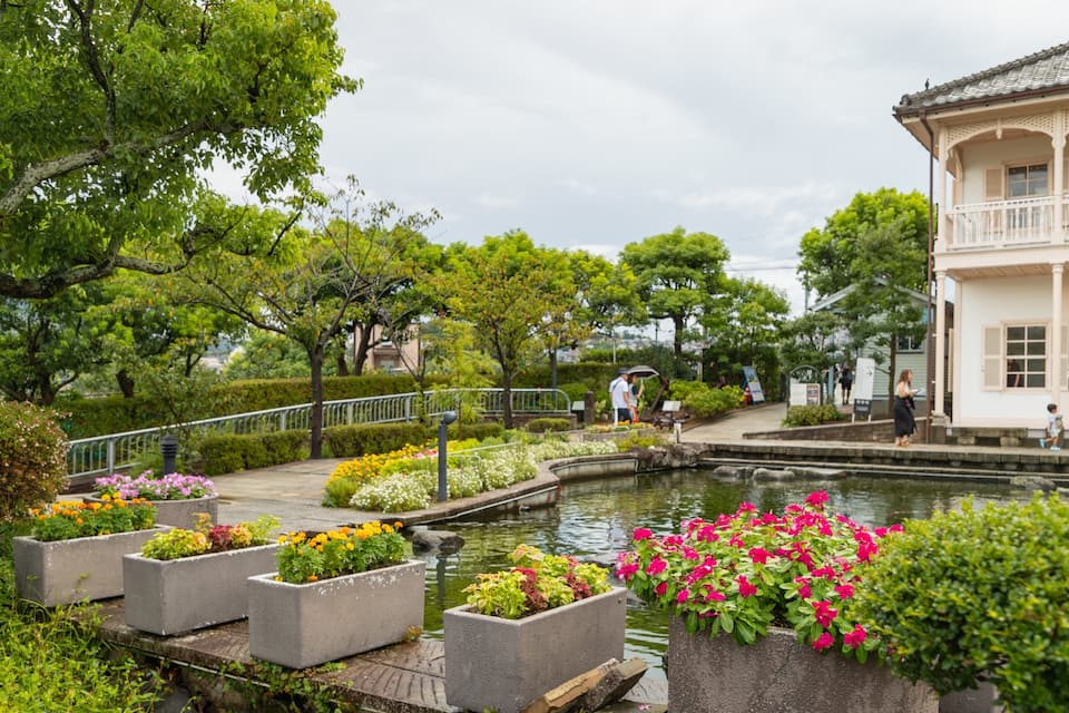 A garden with a pond, flower beds, and a traditional building.