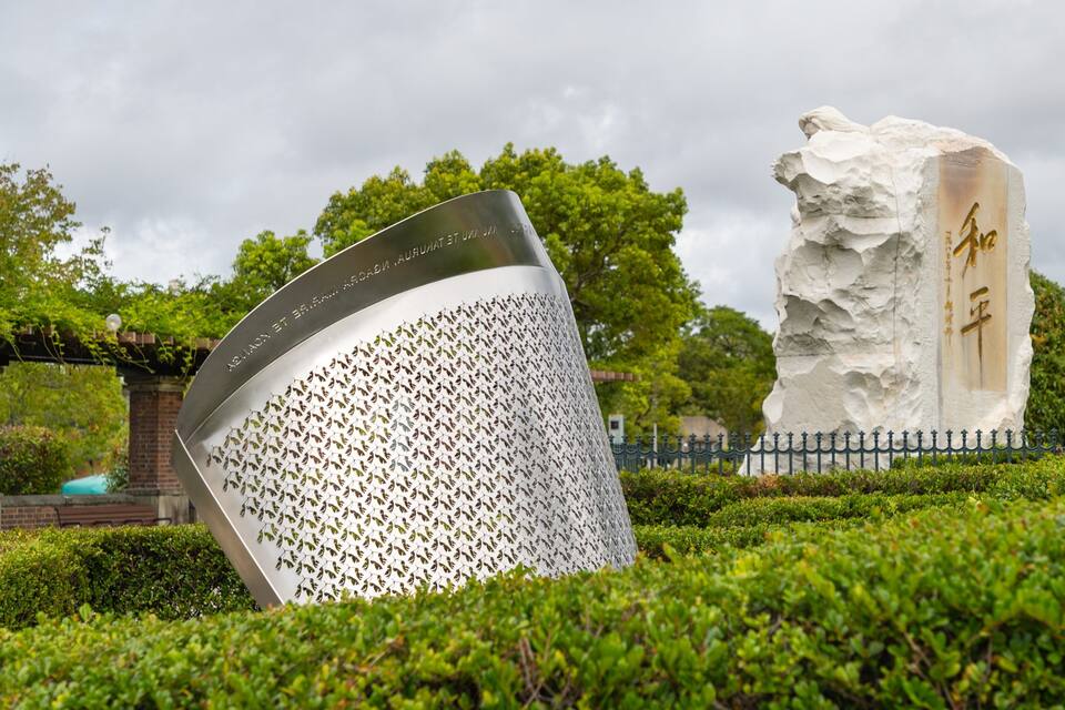 Una scultura in metallo con motivo a foglia e un monumento in pietra con caratteri cinesi.
