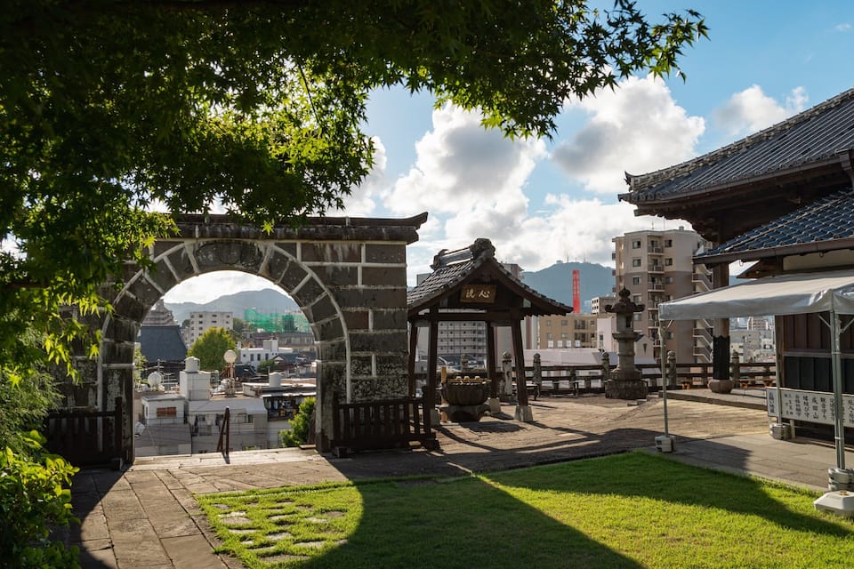 A traditional Japanese gate, a stone lantern, and a pagoda in a park.