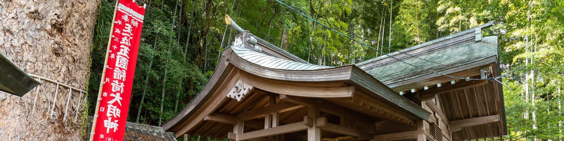A traditional Japanese temple with a red banner, wooden structures, and stone lanterns.