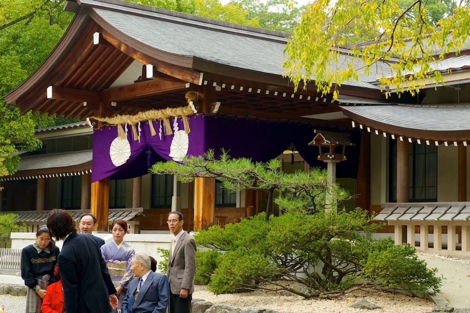 A traditional Japanese building with a curved roof, surrounded by lush greenery and a stone pathway.