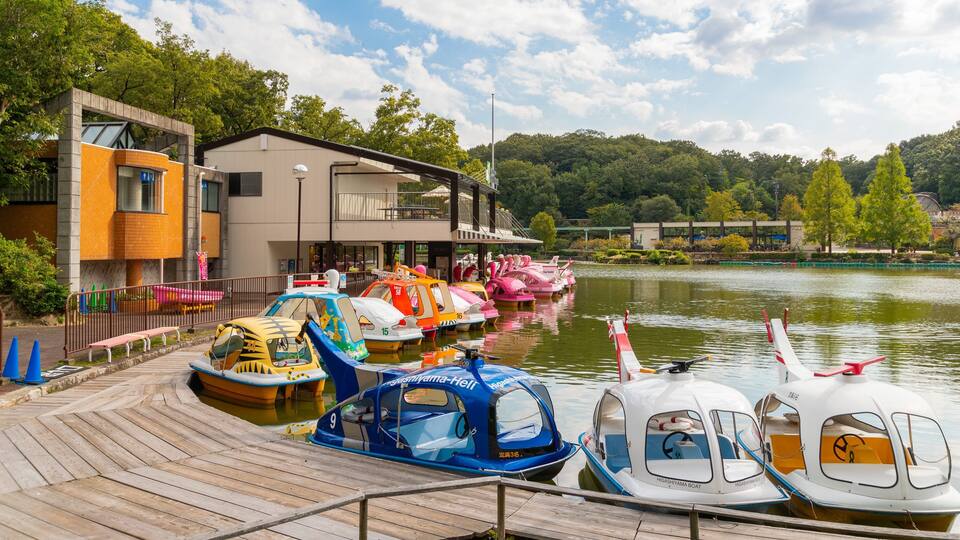 A lakeside dock with colorful boats, a modern building, and lush greenery.
