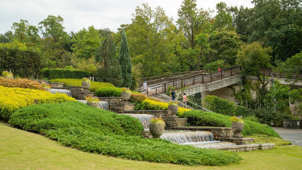 A landscaped garden with a stone bridge, cascading water features, and lush greenery.