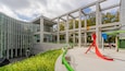 Un ensemble architectural moderne doté de façades en verre, d’un cheminement piétonnier végétalisé et de sculptures abstraites.