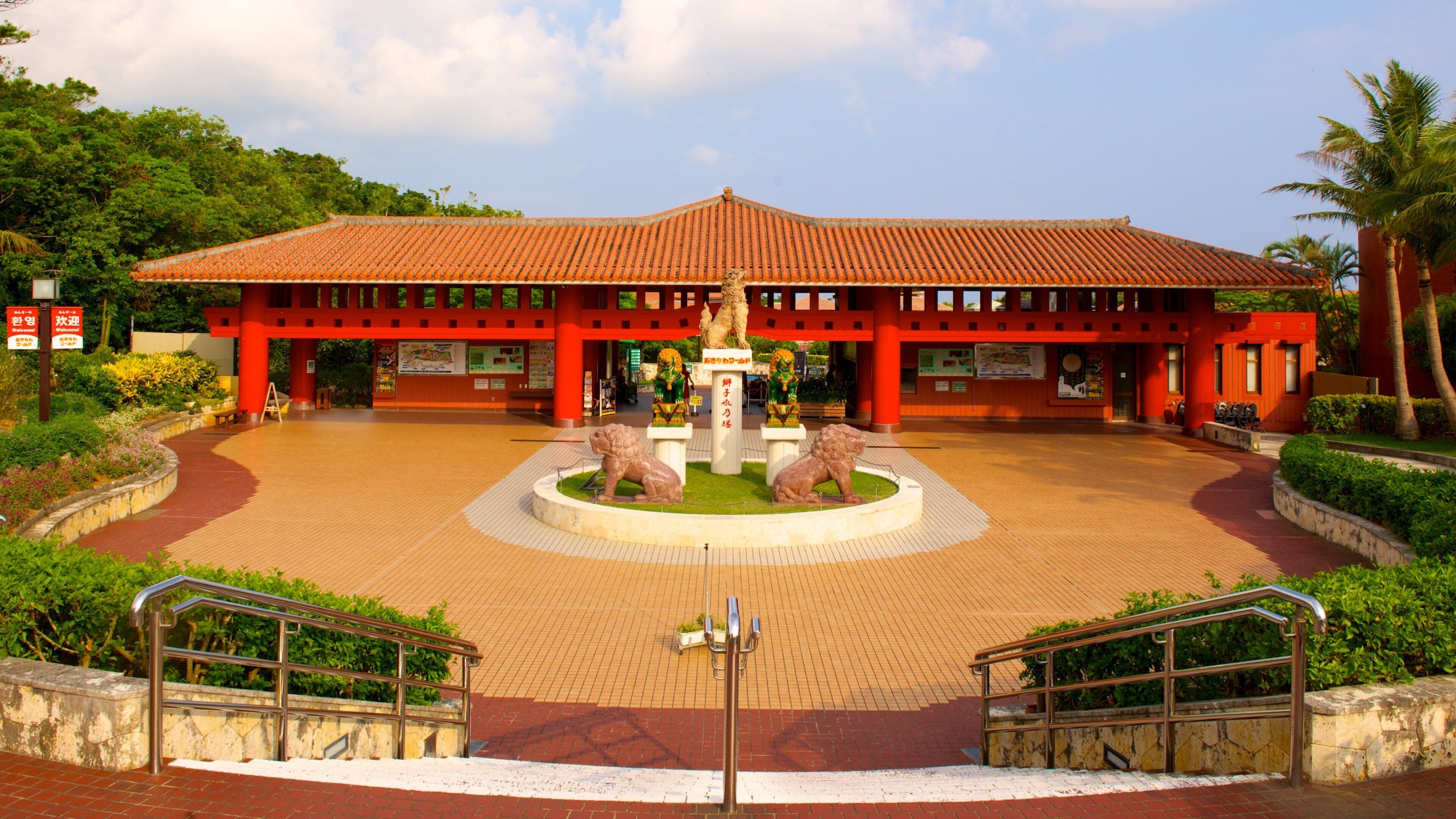 A traditional building with a tiled roof, a central fountain with lion statues, and a surrounding paved area with stairs and railings.
