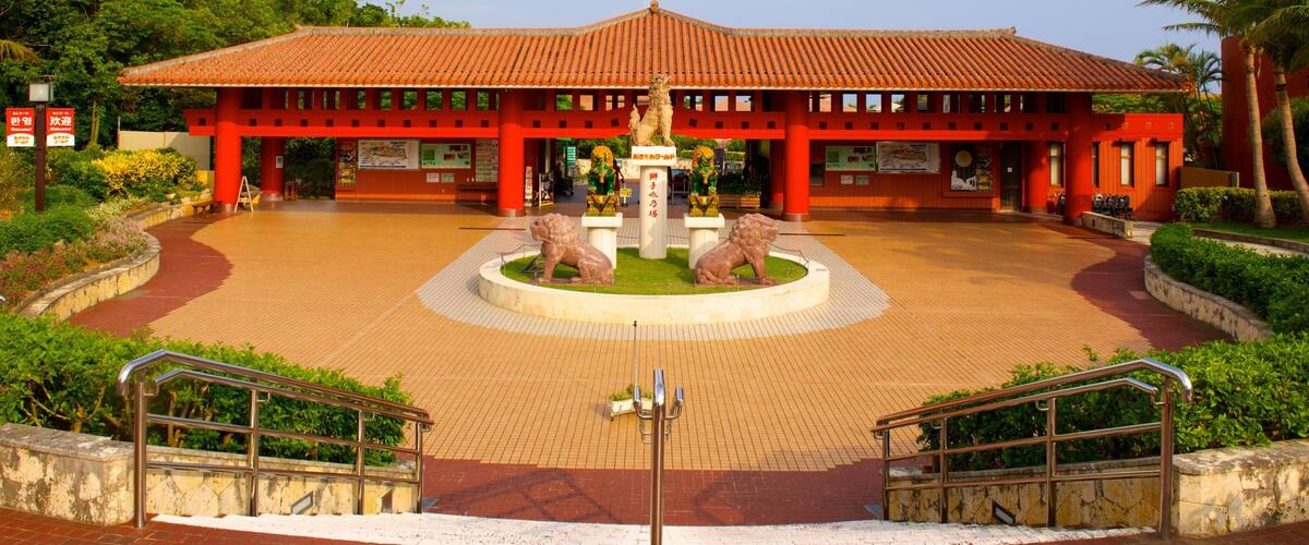 A traditional building with a tiled roof, a central fountain with lion statues, and a surrounding paved area with stairs and railings.