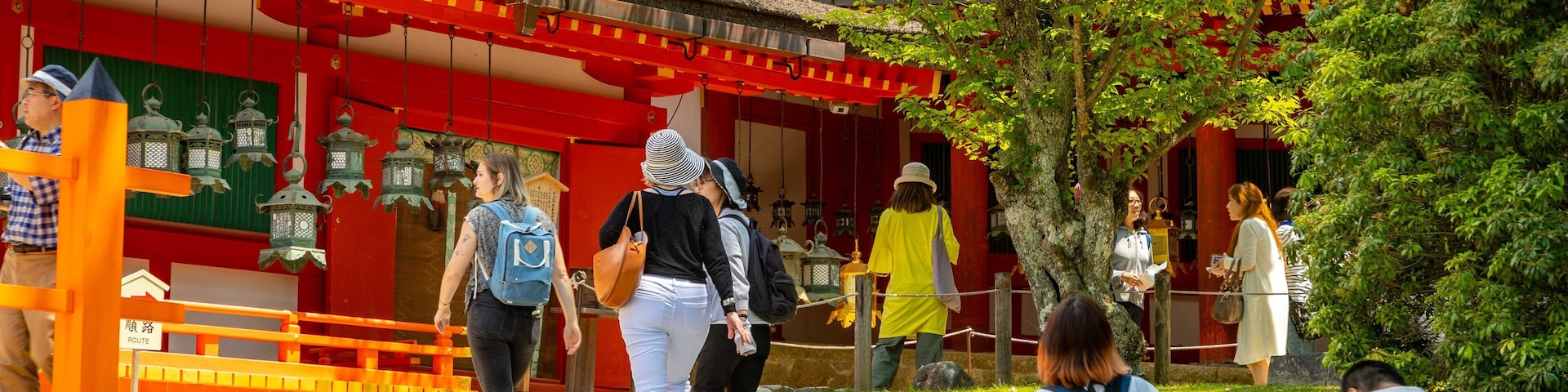 Um templo japonês tradicional com paredes vermelhas e brancas, telhado de telhas e escadaria de pedra que leva à entrada.