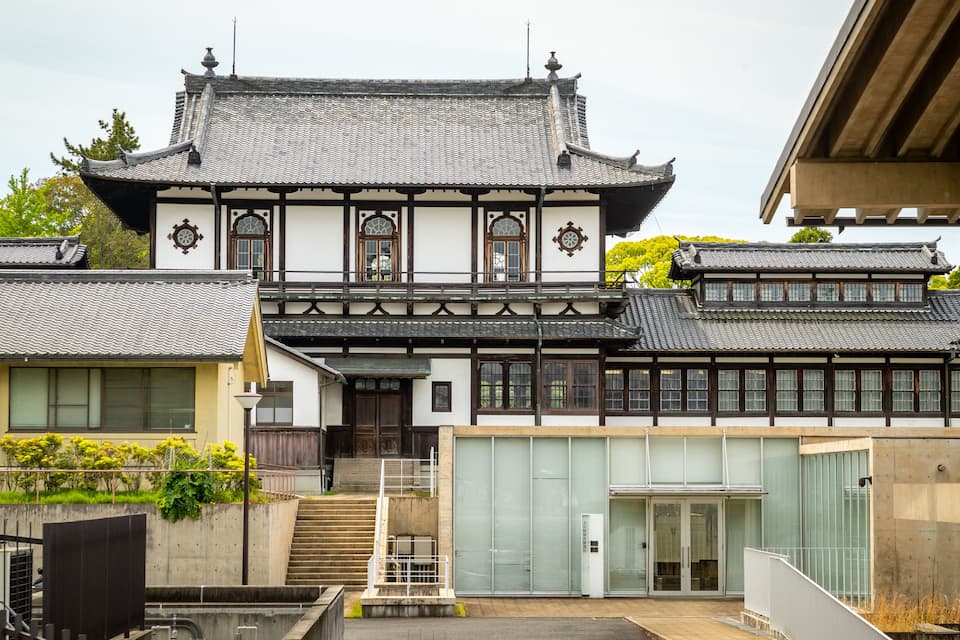 A traditional Japanese building with a tiled roof, wooden beams, and a stone staircase leading to the entrance.