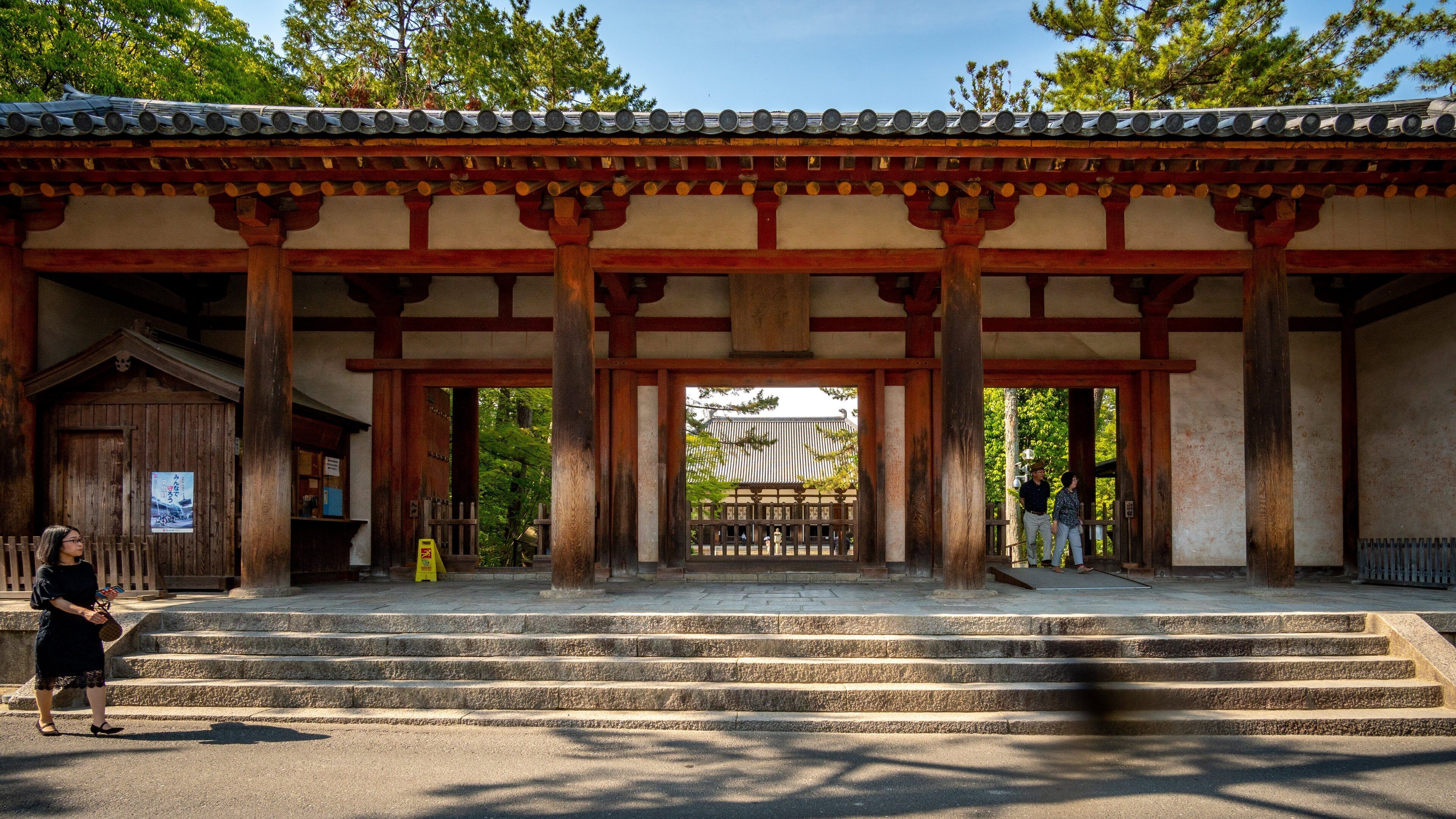 A traditional Japanese gate with wooden pillars and a tiled roof.