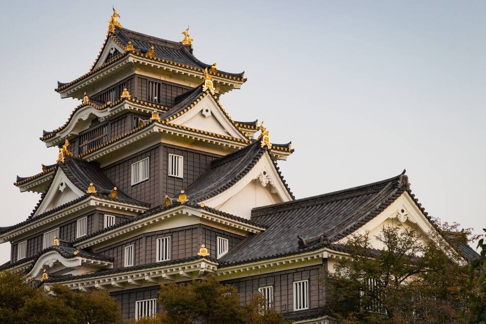 Un castillo japonés tradicional de varios niveles, con elaboradas decoraciones doradas y techos a dos aguas pronunciados.