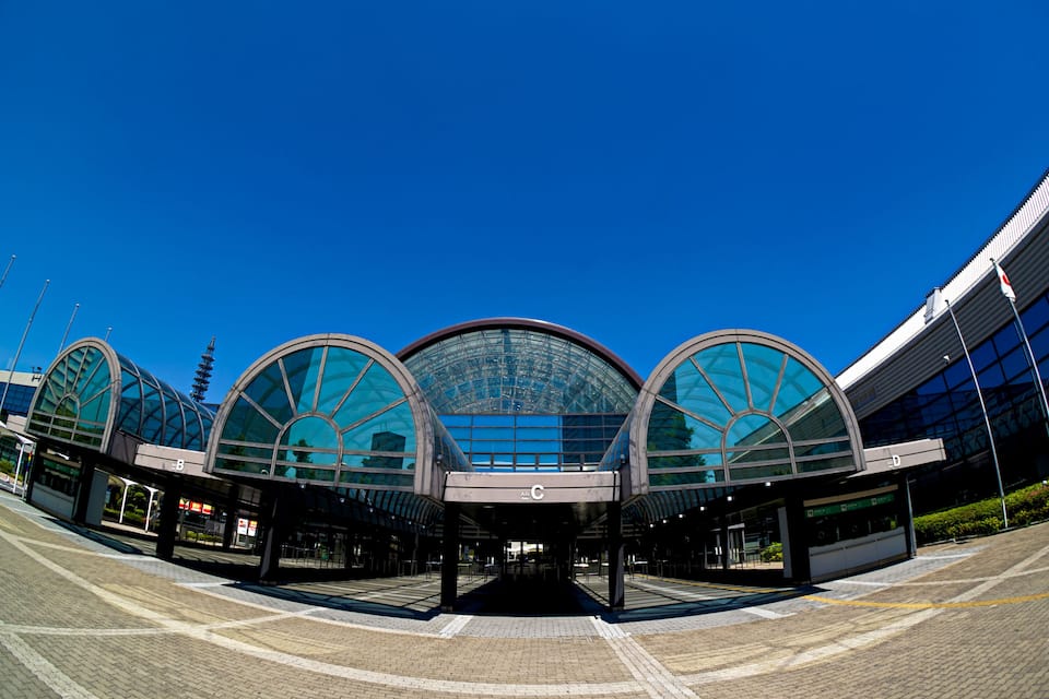 A modern train station with a large glass canopy and multiple curved entrances.