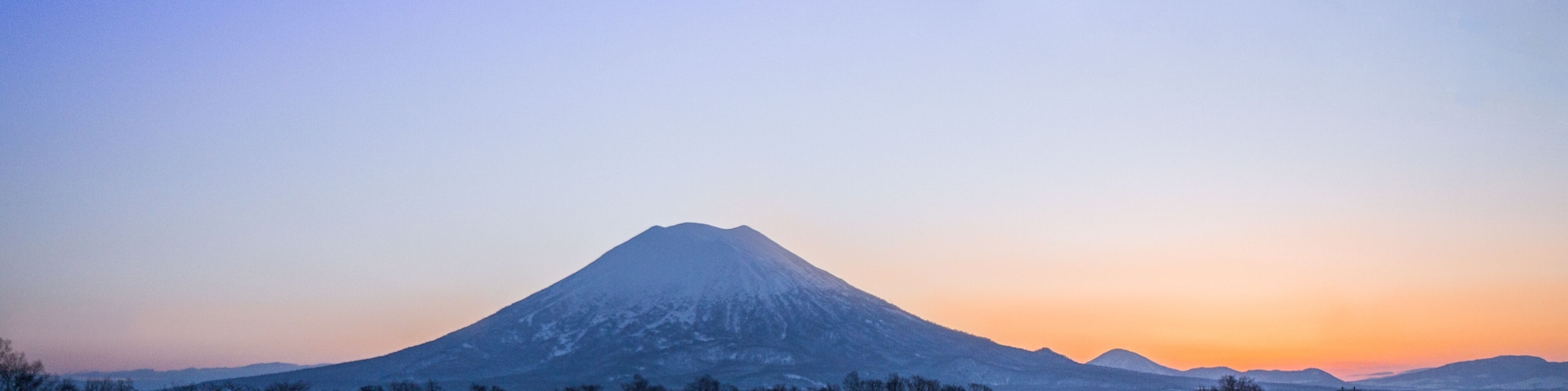 Paisaje nevado con una montaña al fondo y cielo despejado.