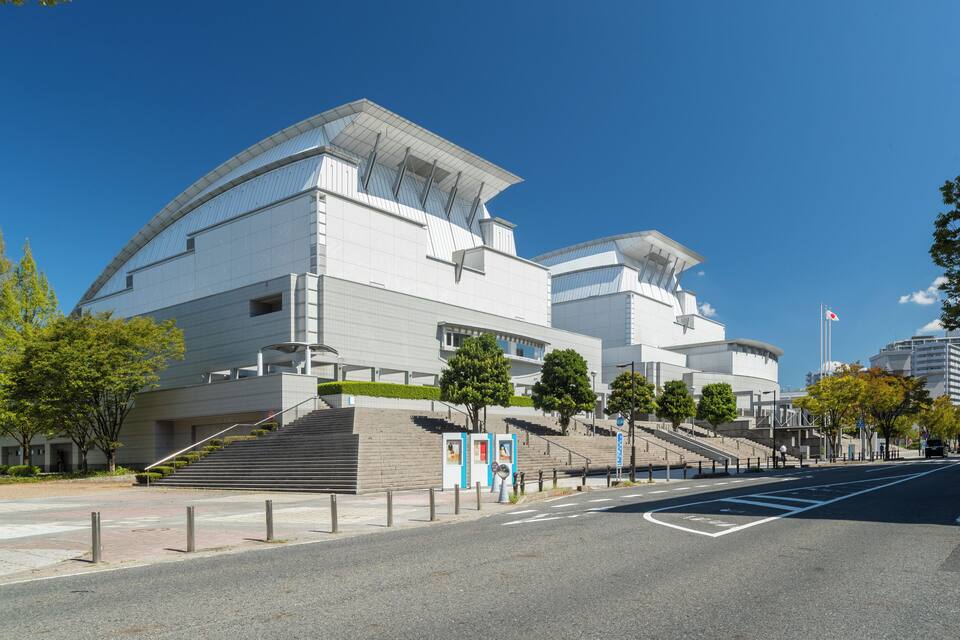 A modern architectural building with a curved roof and a flagpole.