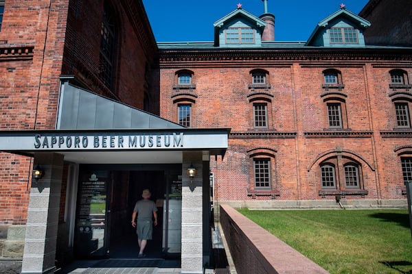 Entrada para o Museu da Cerveja Sapporo, com um edifício de tijolos e um céu azul claro ao fundo.