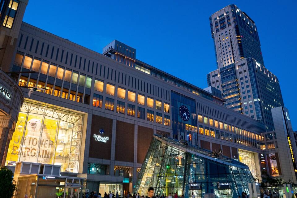 Un centre commercial moderne à l’architecture de verre, doté d’une signalétique lumineuse.
