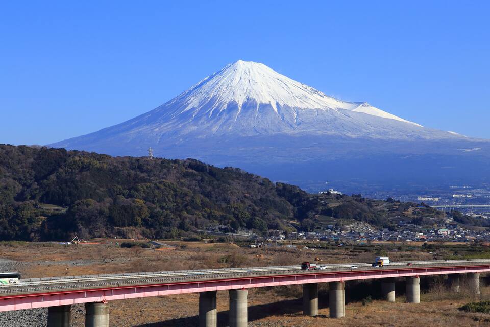 Una montagna innevata, un ponte e un paese sullo sfondo.