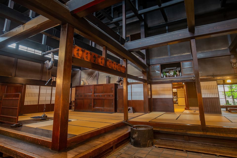 A traditional Japanese interior with tatami flooring, wooden beams, and a shoji screen door.
