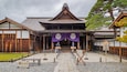 A traditional Japanese building with a tiled roof, wooden beams, and a central entrance flanked by two wooden doors.