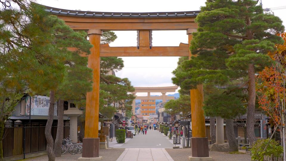 Un torii japonés tradicional con un sendero que lo atraviesa, rodeado de árboles y edificios.