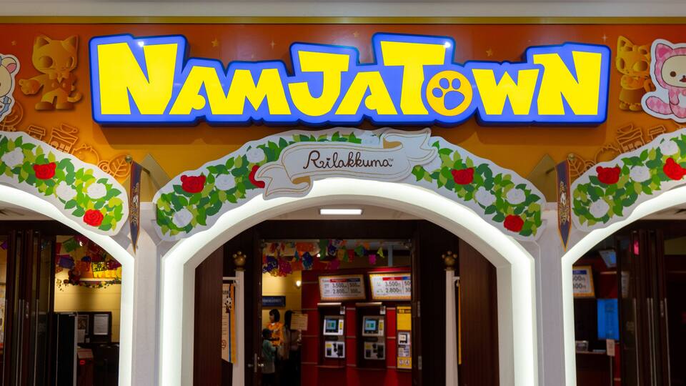 Der Eingang zu NamJatown mit einem Neonzeichen, Blumendekoration und einem Schild mit der Aufschrift 'Rilakkuma'.
