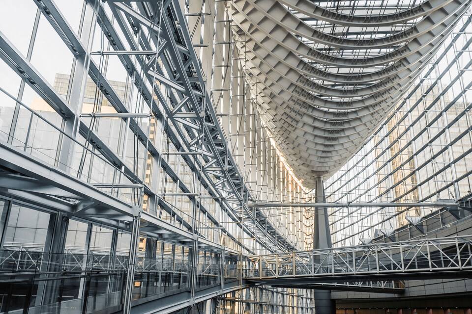 A modern architectural structure with a curved glass facade and a metal framework.