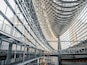A modern architectural structure with a curved glass facade and a metal framework.