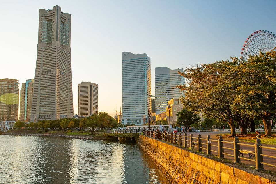 A city skyline with modern skyscrapers, a river, and a Ferris wheel.
