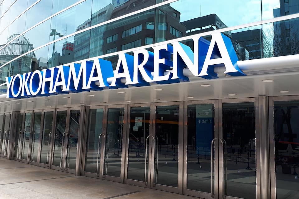 The exterior of the Yokohama Arena with its large glass facade and signage.