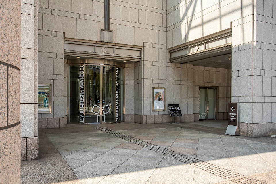 The entrance to the Yokohama Museum of Art with stone walls and a glass door.