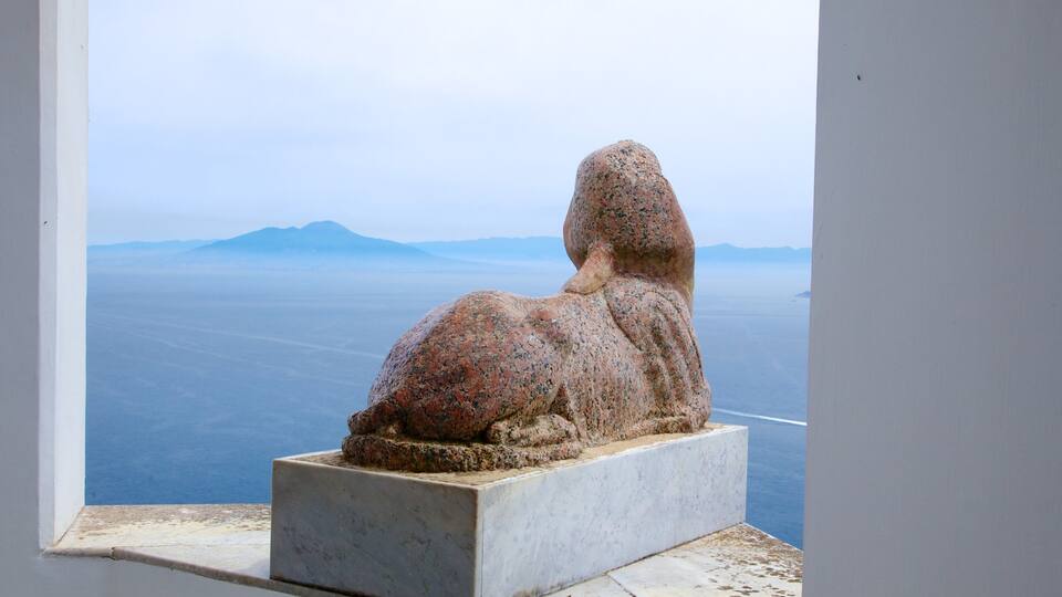 A stone sculpture of a seated figure with a mountainous landscape in the background.
