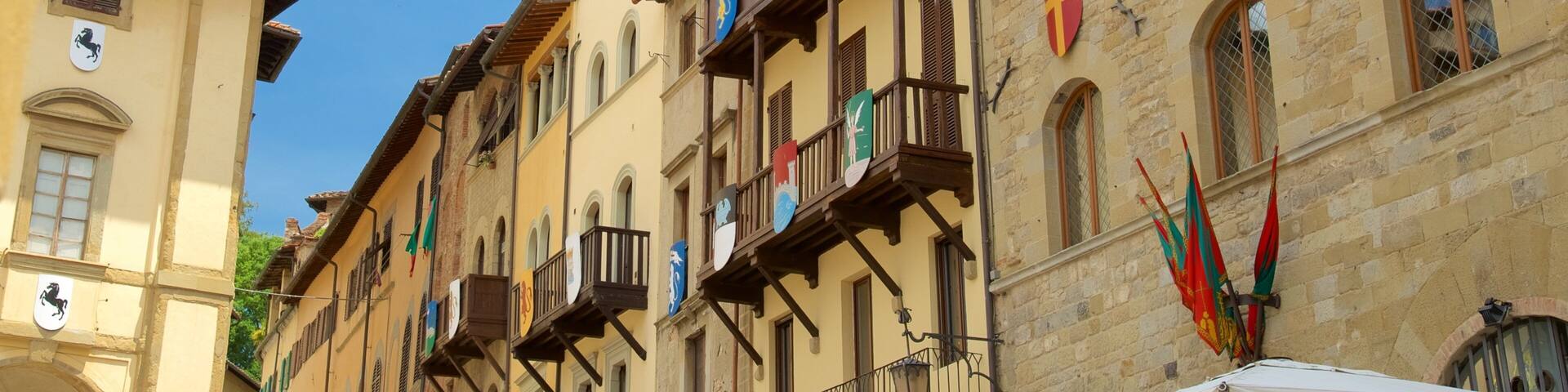 A row of historic buildings with balconies, flags, and a clear blue sky.