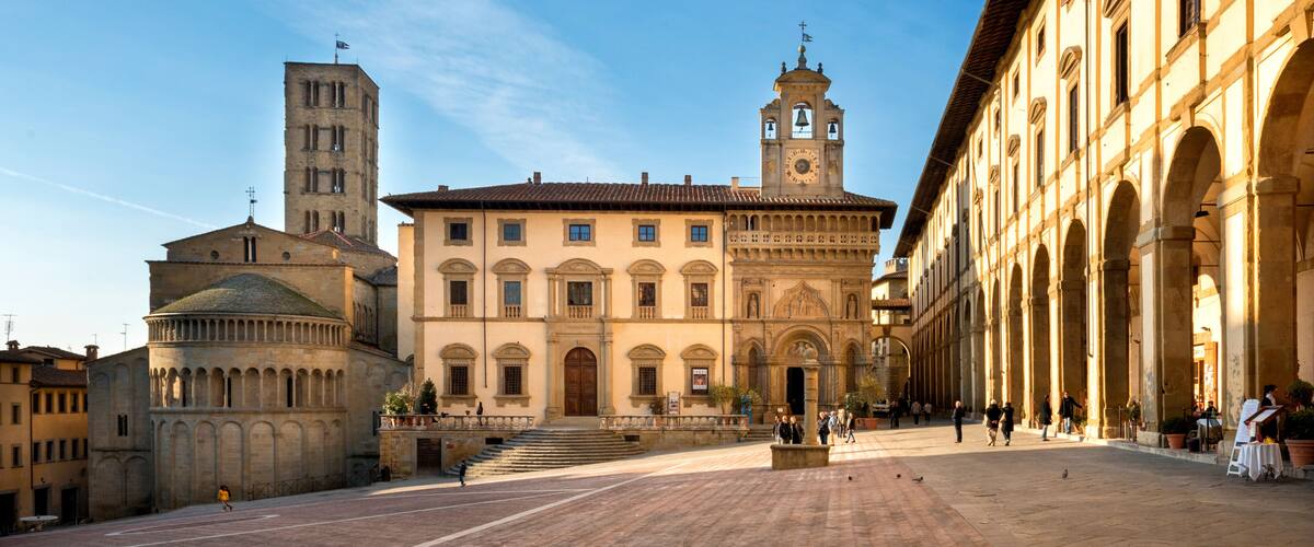 A historic square with a prominent church, a bell tower, and an arched building.