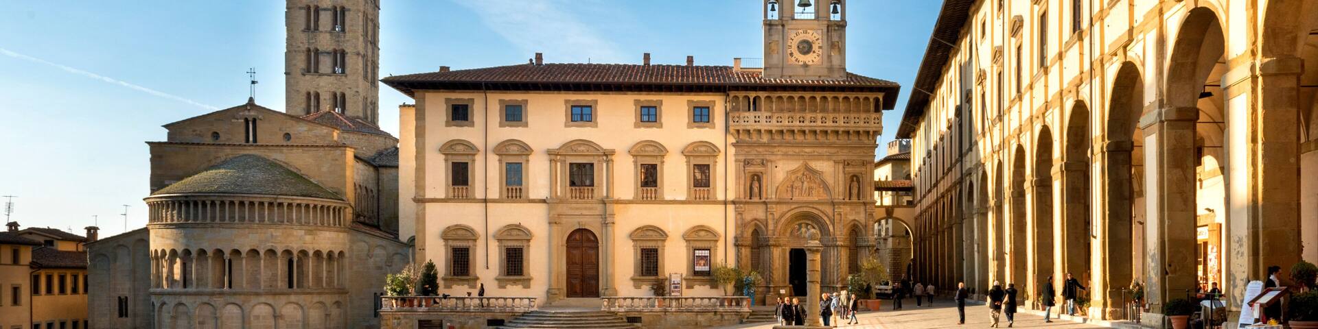 A historic square with a prominent church, a bell tower, and an arched building.