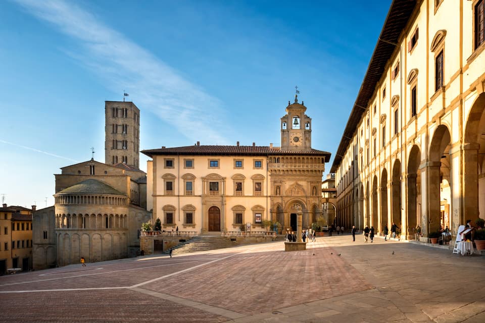 A historic square with a prominent church, a bell tower, and an arched building.