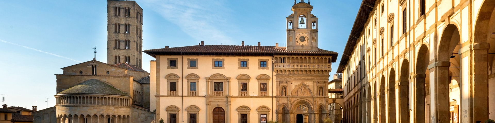 A historic square with a prominent church, a bell tower, and an arched building.