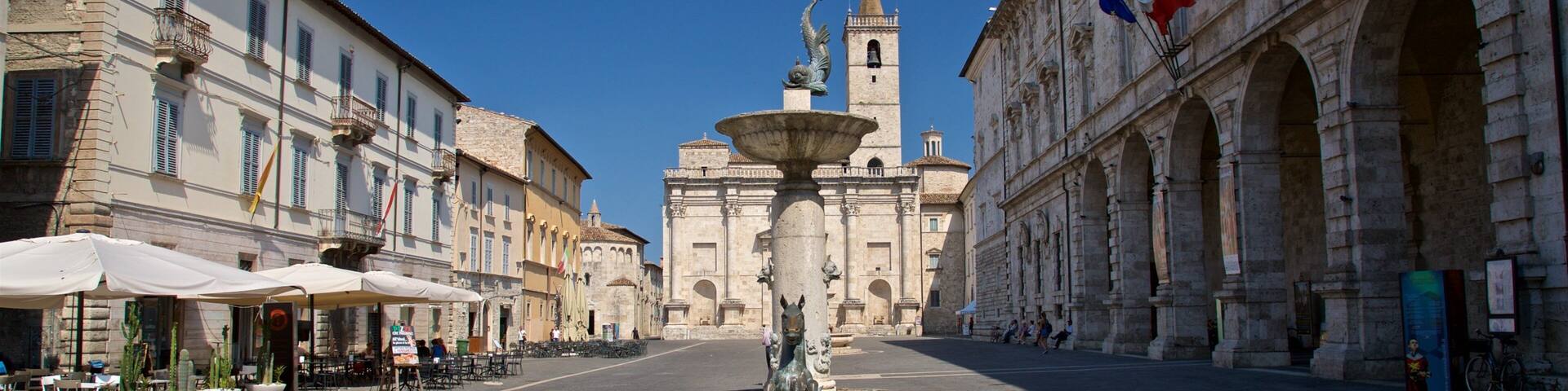 A historic square with a central fountain, surrounded by classical architecture and outdoor seating areas.