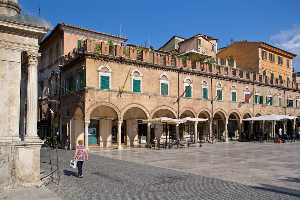 A historic square with a row of arches, cafes, and traditional buildings.