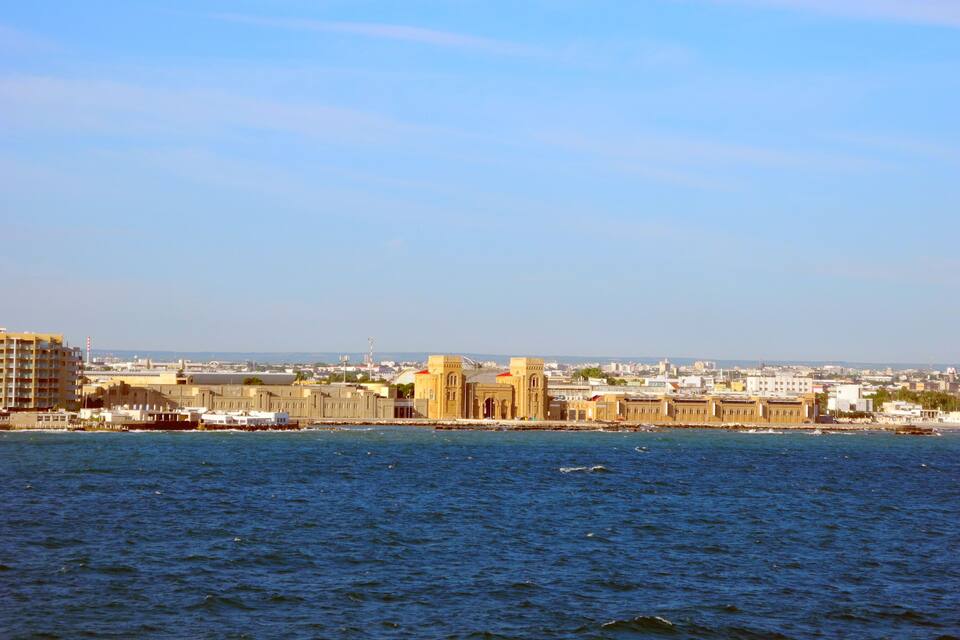 A coastal cityscape with a prominent historic building by the waterfront.