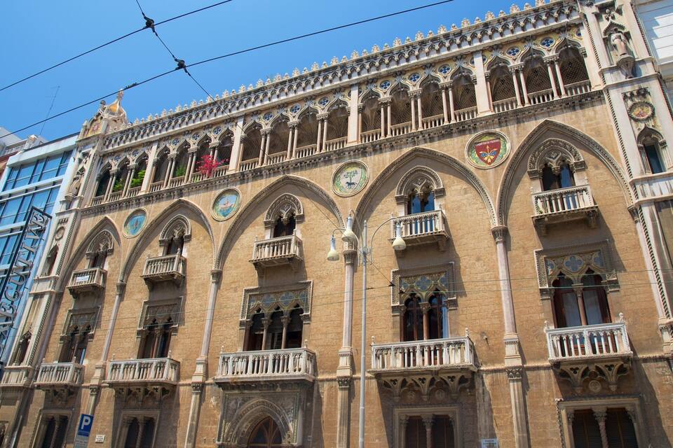 A historic building with ornate Gothic architecture, featuring pointed arches, detailed stone carvings, and a series of balconies.