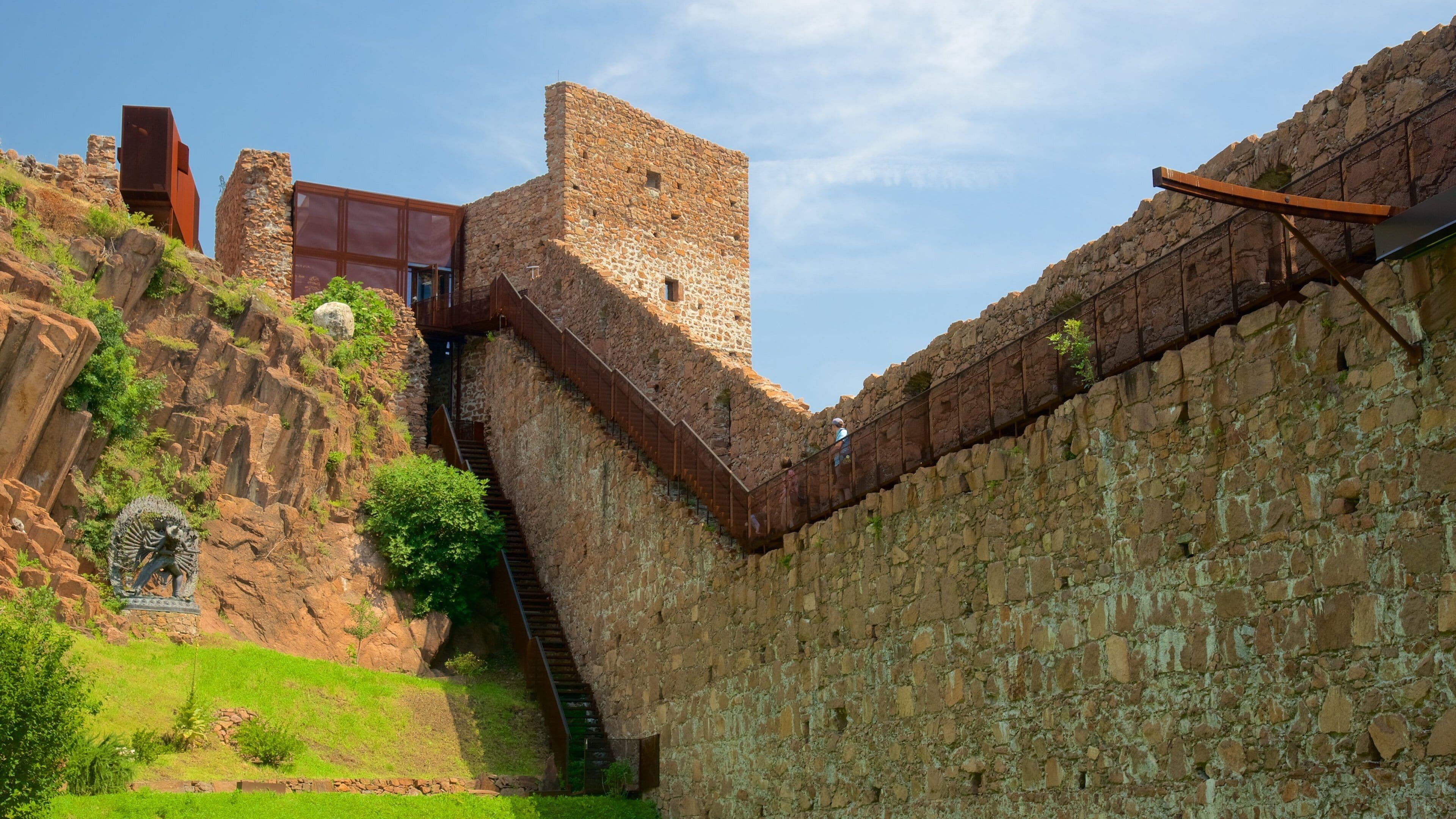 Een historische stenen muur met een trap die naar een toren leidt.