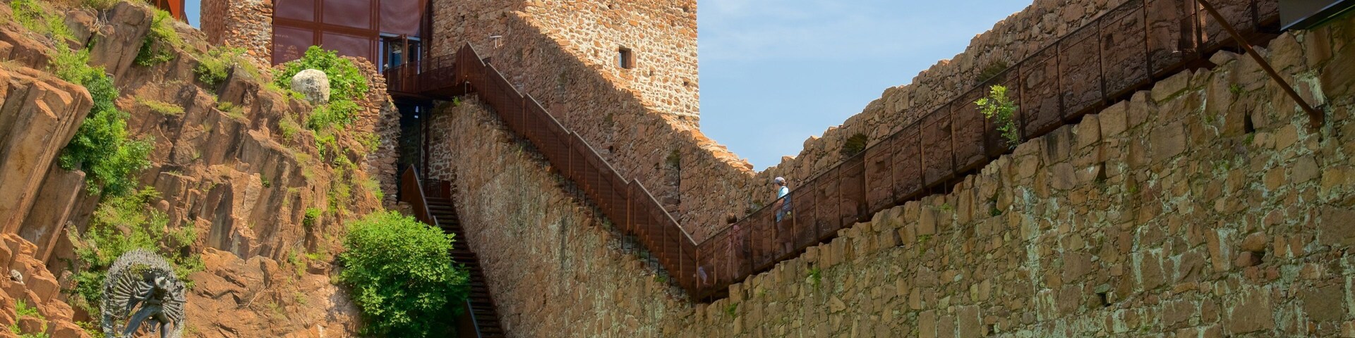 Um muro de pedra histórico com uma escadaria que sobe até uma torre.