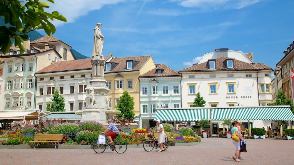 Ein Stadtplatz mit einer Statue, farbenfrohen Gebäuden und dem Hotel 'Hotel Greif'.