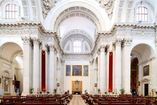 L’intérieur d’une église richement décorée, avec de hauts plafonds, des rideaux de velours rouge et des colonnes de style classique.