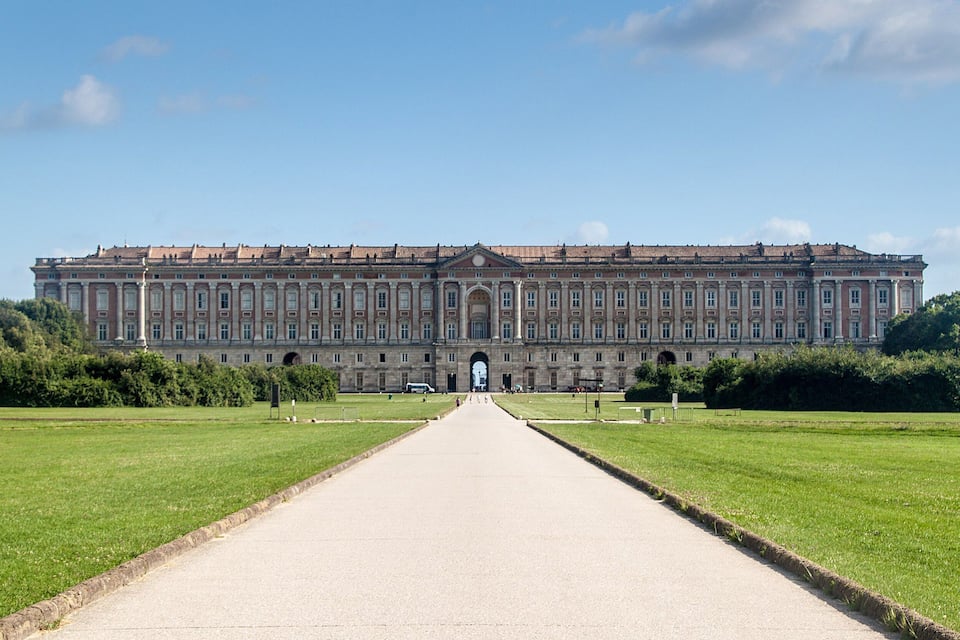A large, symmetrical building with a central entrance, surrounded by well-maintained lawns and a clear sky.