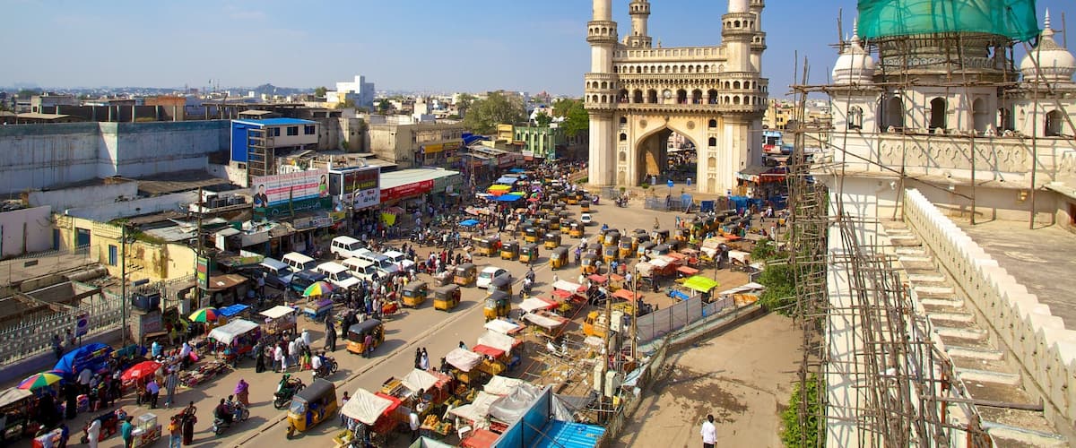 A busy market area with a prominent historical archway and a mosque with scaffolding.