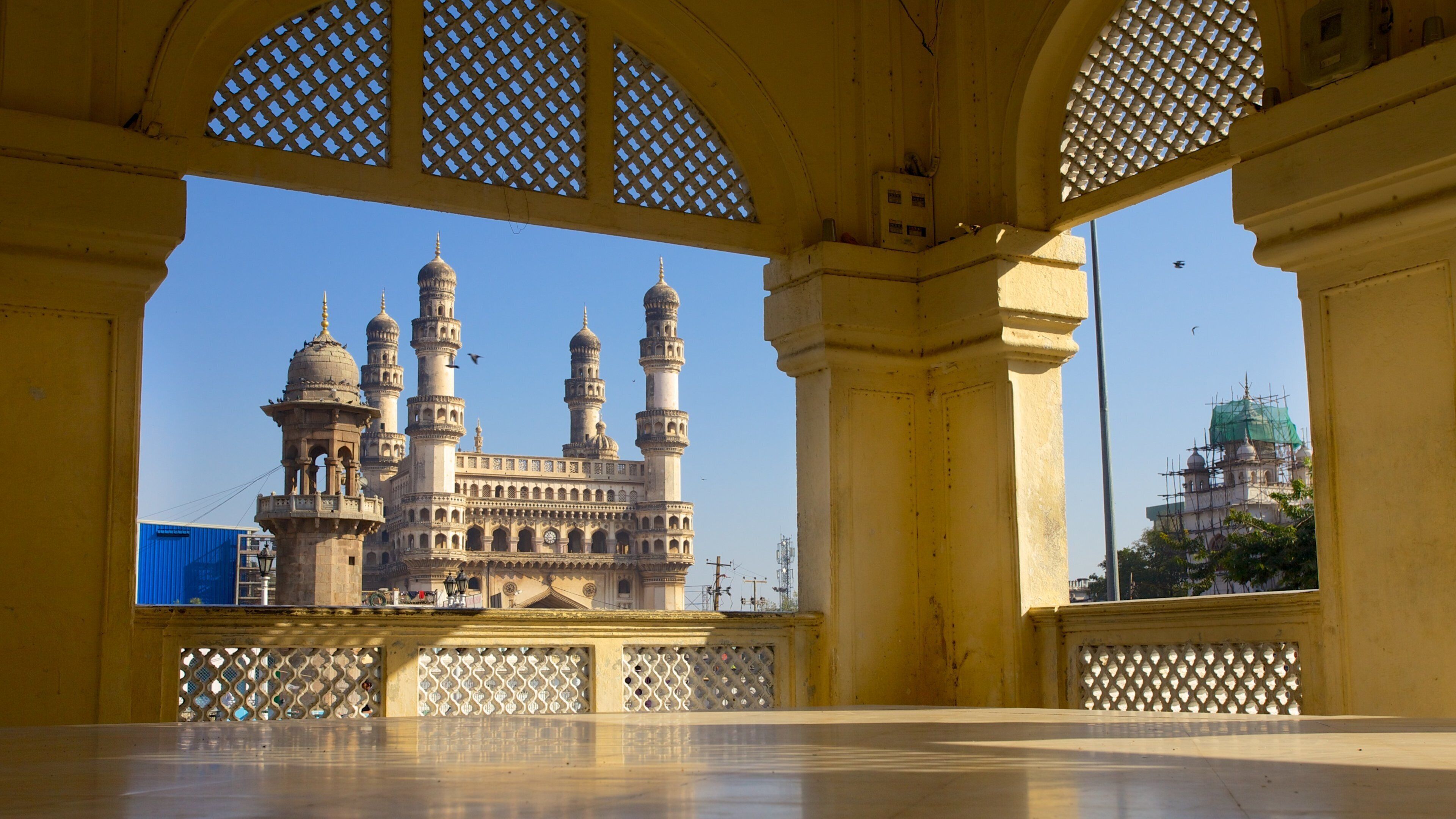 A historic building with multiple domes and minarets, viewed through a yellow structure with lattice windows.