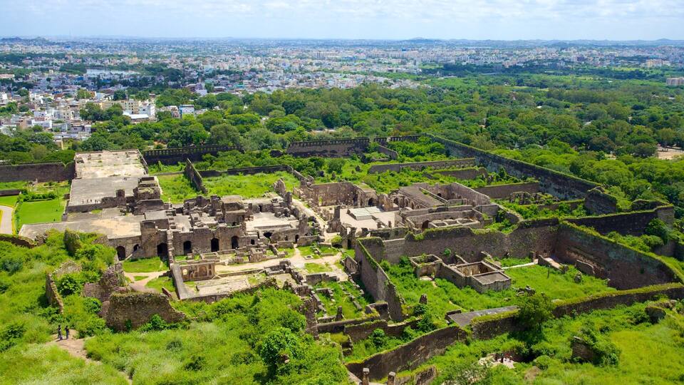 An ancient fortress surrounded by lush greenery, with a cityscape in the background.