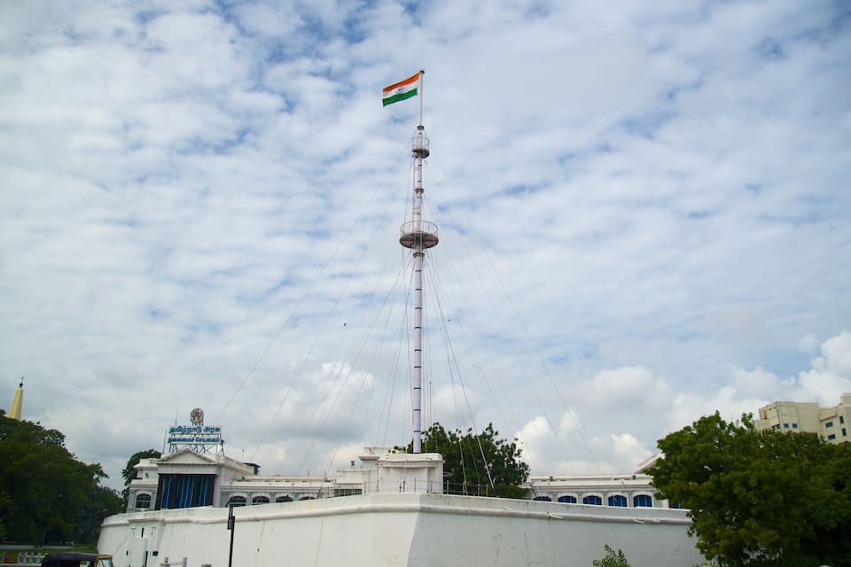 Una torre alta amb una bandera, envoltada d'edificis i arbres.