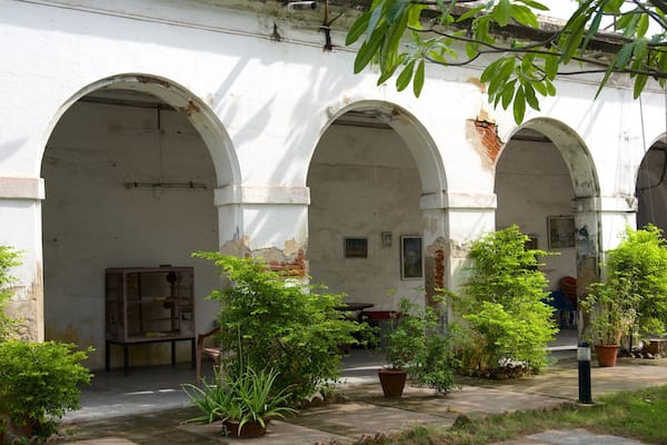 Une cour intérieure agrémentée d’arcades, de plantes en pot et d’un bâtiment au style rustique.